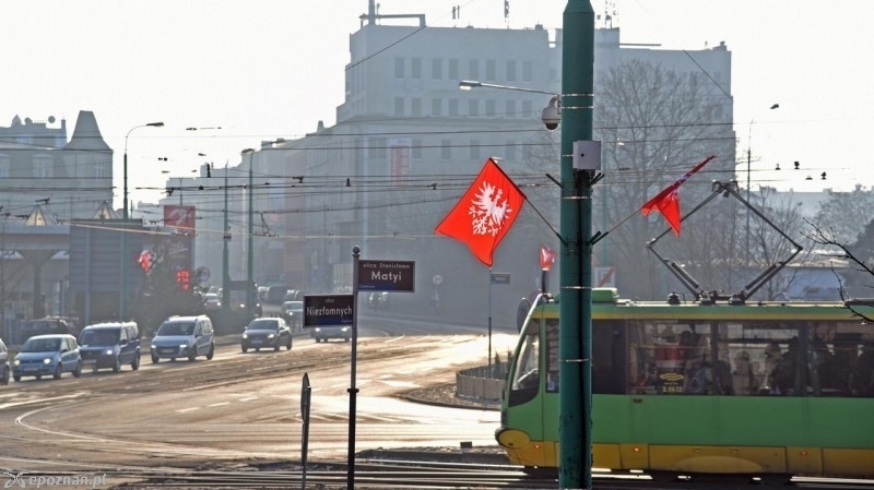 Tramwaj MPK Poznań udekorowany proporcami powstańczymi na skrzyżowaniu przy pomniku Powstańców Wielkopolskich.