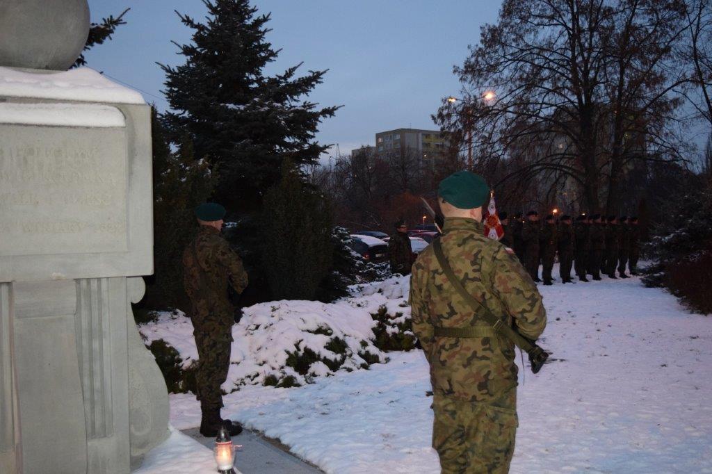 Asysta honorowa żołnierzy stojąca przed pomnikiem.