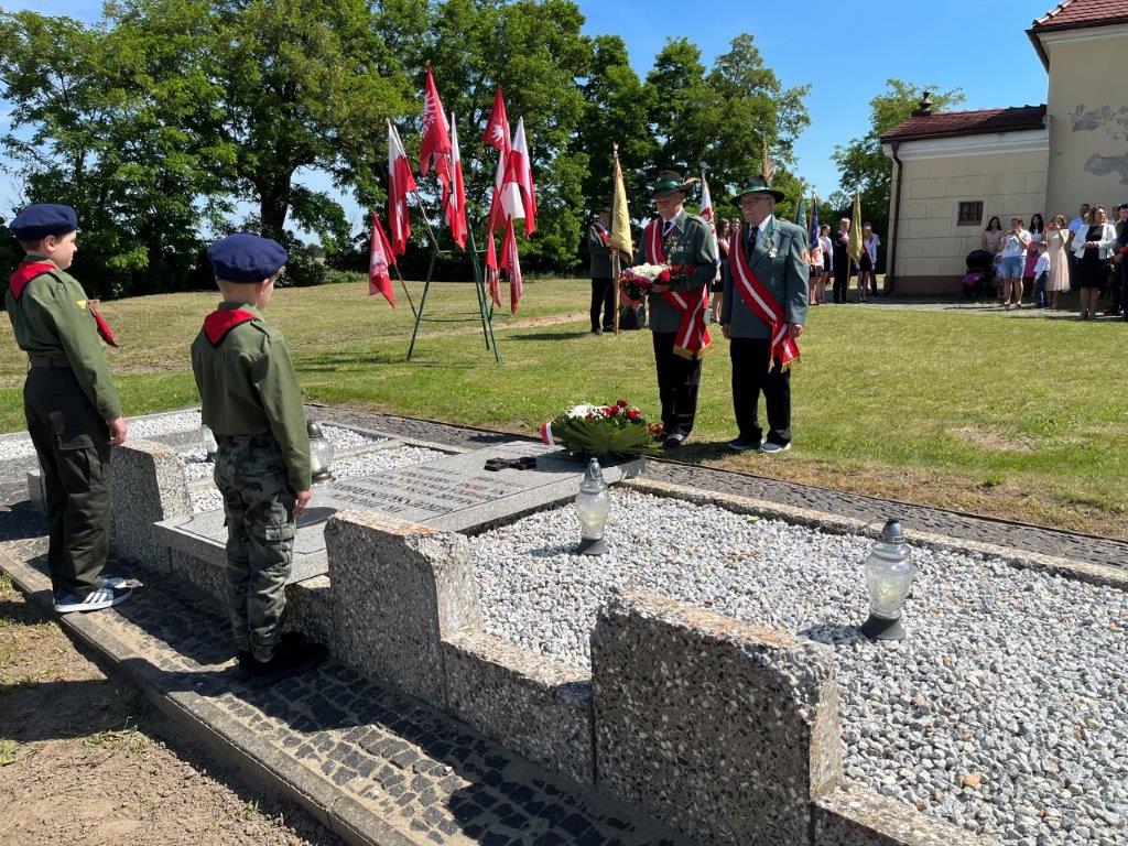 Delegacja Bractwa Kurkowego składa wiązankę kwiatów na grobie majora, dwóch harcerzy pełni wartę, w tle pozostali uczestnicy.