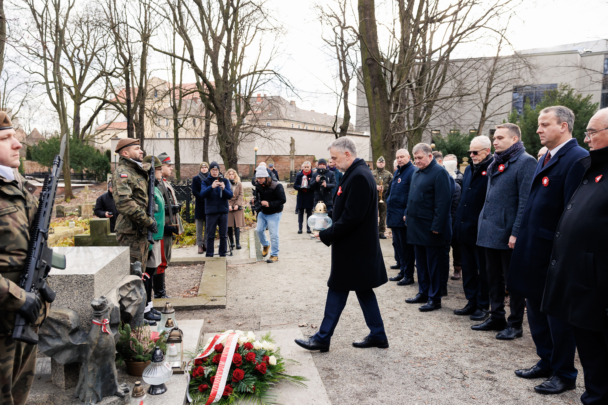 Mężczyzna składający znicz przy grobie.