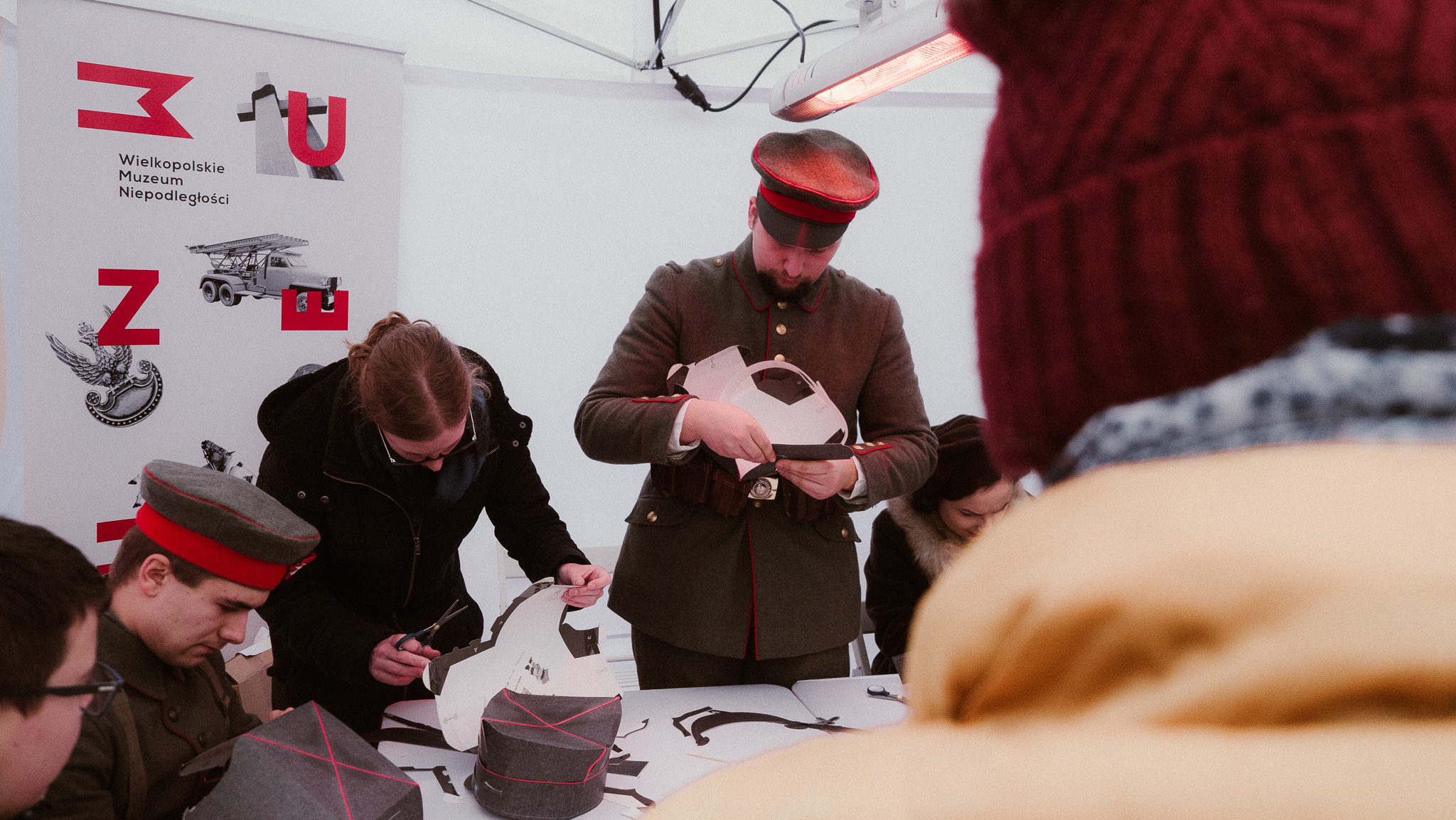 Mężczyzna w mundurze powstańczym składający ozdoby powstańcze.