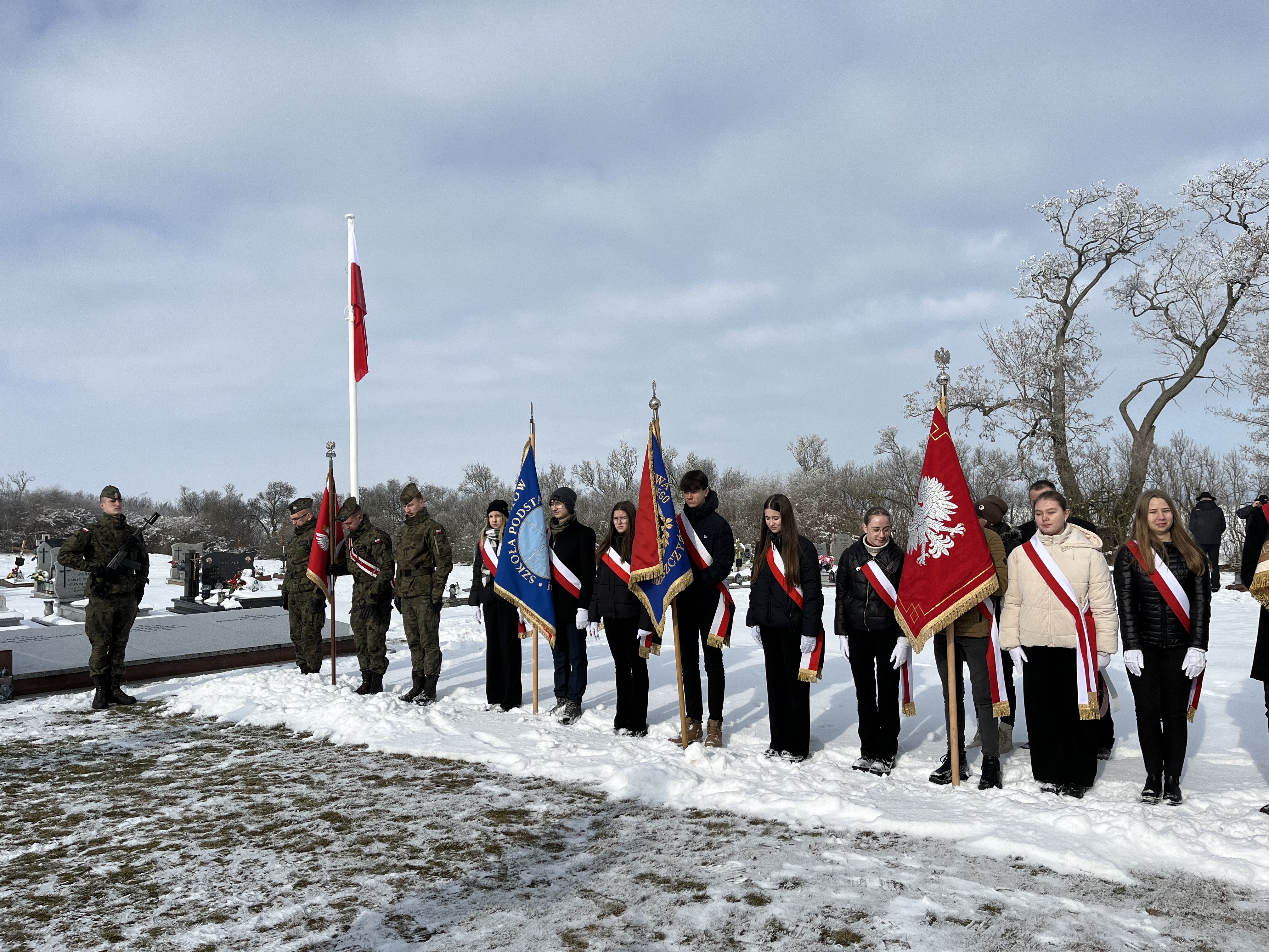 Na zdjęciu poczty sztandarowe 16. Jarocińskiego Batalionu Remontu Lotnisk im. gen. bryg. S. Taczaka, Zespołu Szkół Przyrodniczo-Biznesowych im. J. Dziubińskiej w Tarcach, Szkoły Podstawowej im. A. Mickiewicza w Żerkowie, Szkoły Podstawowej im. ks. J. Twardowskiego w Dobieszczyźnie, Szkoły Podstawowej im. Powstańców Wielkopolskich w Komorzu Przybysławskim i Kurkowego Bractwa Strzeleckiego w Żerkowie podczas uroczystości w Łgowie, 16.02.2025 r.